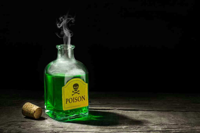 Green poison bottle with cork on wooden surface.