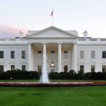 The White House with a fountain in the foreground and an American flag flying