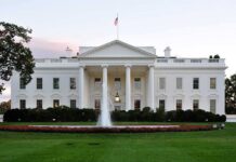 The White House with a fountain in the foreground and an American flag flying