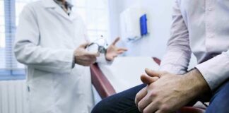 A doctor in a white coat discussing with a patient sitting on an examination table