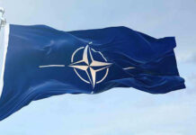 NATO flag waving against blue sky.