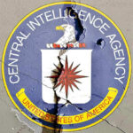 Cracked CIA logo on weathered wall.
