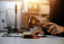 Tiger King Lawyer BUSTED — Fake AI Citations Hand holding gavel with scales in background.