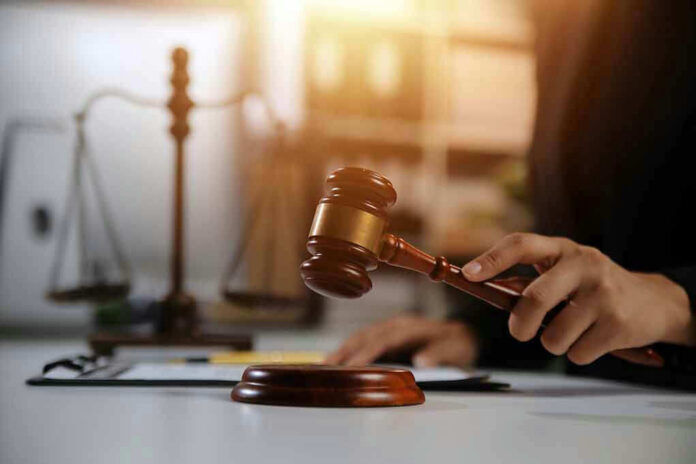 Hand holding gavel with scales in background.