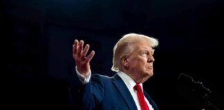 A man in a suit gesturing during a speech