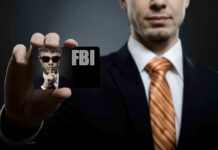 A man in a suit holding an FBI identification card while making a shushing gesture