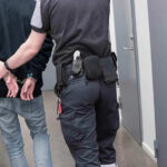 Green Bay Star’s Felony Drama Unfolds Officer escorting handcuffed person down hallway.