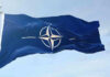 Russian Drone HITS NATO Territory – Unprecedented Crisis NATO flag waving against blue sky.