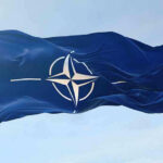 Russian Drone HITS NATO Territory – Unprecedented Crisis NATO flag waving against blue sky.