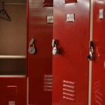 Woke Locker Room Turmoil Spurs DOJ Intervention Red lockers with padlocks, one open with hanger.