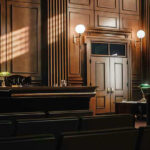 Trump’s $83M Defamation: Shocking Twist! Empty courtroom with judges bench and wooden decor.