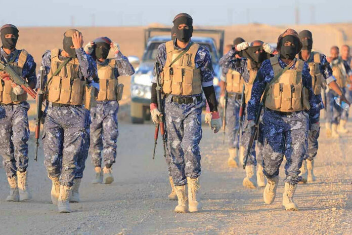 2446565389 Camouflaged soldiers wearing masks and vests walk in desert.