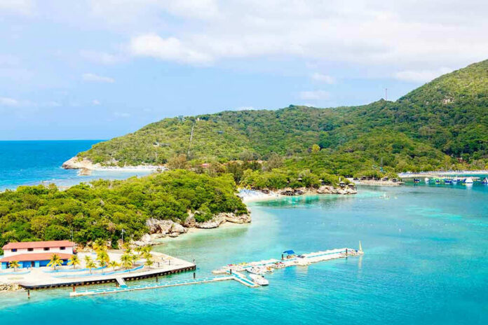 Tropical beach with docks and lush green hills.