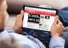 Person reading tablet with headline Scandal Unfolds.
