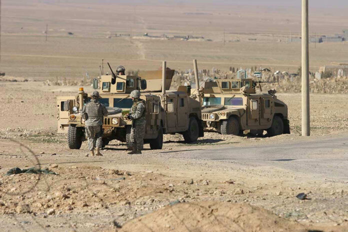 Soldiers beside military vehicles in a desert area.