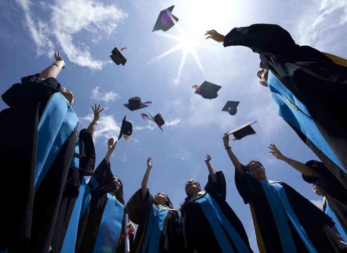 shutterstock_115335829 Graduating students celebrating by throwing their caps into the air under a bright blue sky