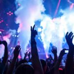 Foiled Attack: Taylor Swift Concert Terror Plot Thwarted Crowd at a concert with hands raised and smoke effects in the background