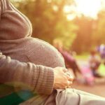 America’s Depopulation Dilemma Uncovered Pregnant woman sitting on a bench in a park during sunset
