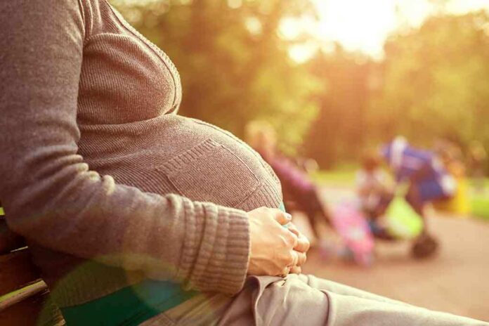 shutterstock_150533705 Pregnant woman sitting on a bench in a park during sunset