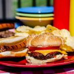 Junk Food REWIRES Kids’ Brains! A plate with a hamburger, hot dog, and potato chips on a picnic table