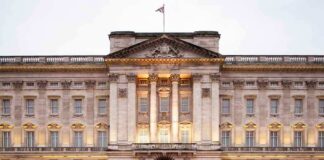 Front view of Buckingham Palace with illuminated facade and British flag