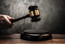 Massive Fraud Scheme: 41-Year Sentence for Nonprofit Chief A hand holding a gavel above a wooden block