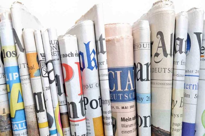 A collection of rolled newspapers displaying various headlines and designs