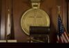 Judge SHOCKS With Evidence Ruling – Murder Weapon Stays! A judges bench in a courtroom with a gavel and flags