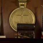 A judges bench in a courtroom with a gavel and flags