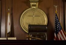 A judges bench in a courtroom with a gavel and flags