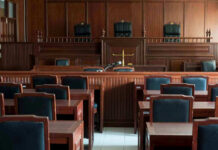 On-Duty Cop Convicted In Child Assault Empty courtroom with wooden furnishings and judges bench.
