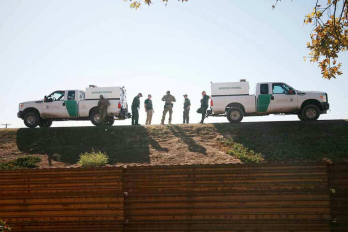 1243518340 Border Patrol vehicles and agents on a ridge.