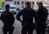 Bomb Drama Grips Chase Bank— FBI Opens Fire Three police officers standing on a city street.