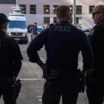 Bomb Drama Grips Chase Bank— FBI Opens Fire Three police officers standing on a city street.