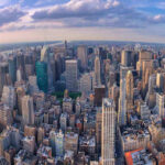 Rent Freeze Gambit Triggers NYC Alarm Aerial view of city with skyscrapers and cloudy sky.
