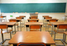 School Locker Room Rumor Swirls — Predatory Teacher Empty classroom with desks and a chalkboard.