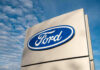 Trump Slams Auto Repair Lockdown Ford logo sign against blue sky.