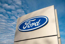 Trump Slams Auto Repair Lockdown Ford logo sign against blue sky.
