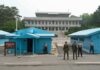 Strait Reopens, Bomb Clock Ticks Military personnel standing near blue buildings at a border crossing