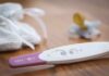 Abortion Firestorm Engulfs YouTube Star A pregnancy test next to a pacifier and a knitted baby hat on a wooden surface