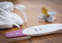Abortion Firestorm Engulfs YouTube Star A pregnancy test next to a pacifier and a knitted baby hat on a wooden surface