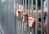 Murderers on ‘Early Release’ List? Hands gripping metal prison bars