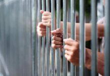 Murderers on ‘Early Release’ List? Hands gripping metal prison bars