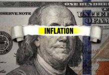 Price Spike Slams America—What’s Driving It? A torn paper strip with the word 'INFLATION' over a hundred dollar bill featuring Benjamin Franklin