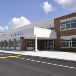 Fired Over ‘Kissing Skits’ — Back Teaching Kids Modern school building with large windows and a clear sky