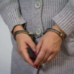 Prosecutors Push Cult Plot — Due Process Snags A person wearing handcuffs with their hands clasped together
