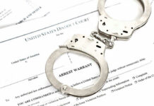 Inside Job: 100 Detroit Homes Vanish Handcuffs on top of an arrest warrant document.