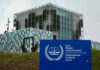 Sanction Hammer Drops — Judges Panic International Criminal Court building with sign in foreground.