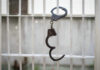 Handcuffs hanging on a barred window.