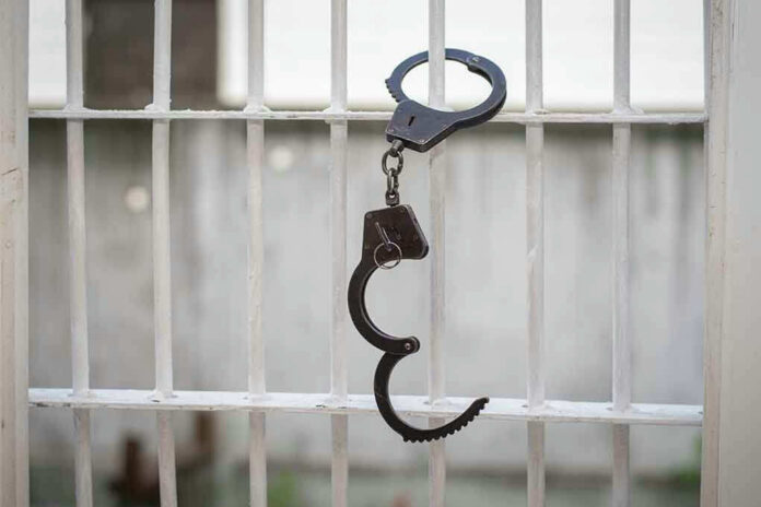 680970664 Handcuffs hanging on a barred window.